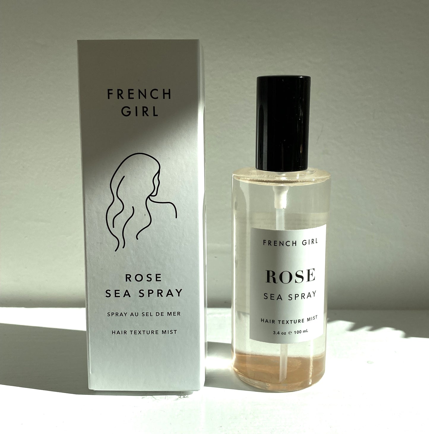 French Girl Hair Sea Spray glass bottle next to its white box.