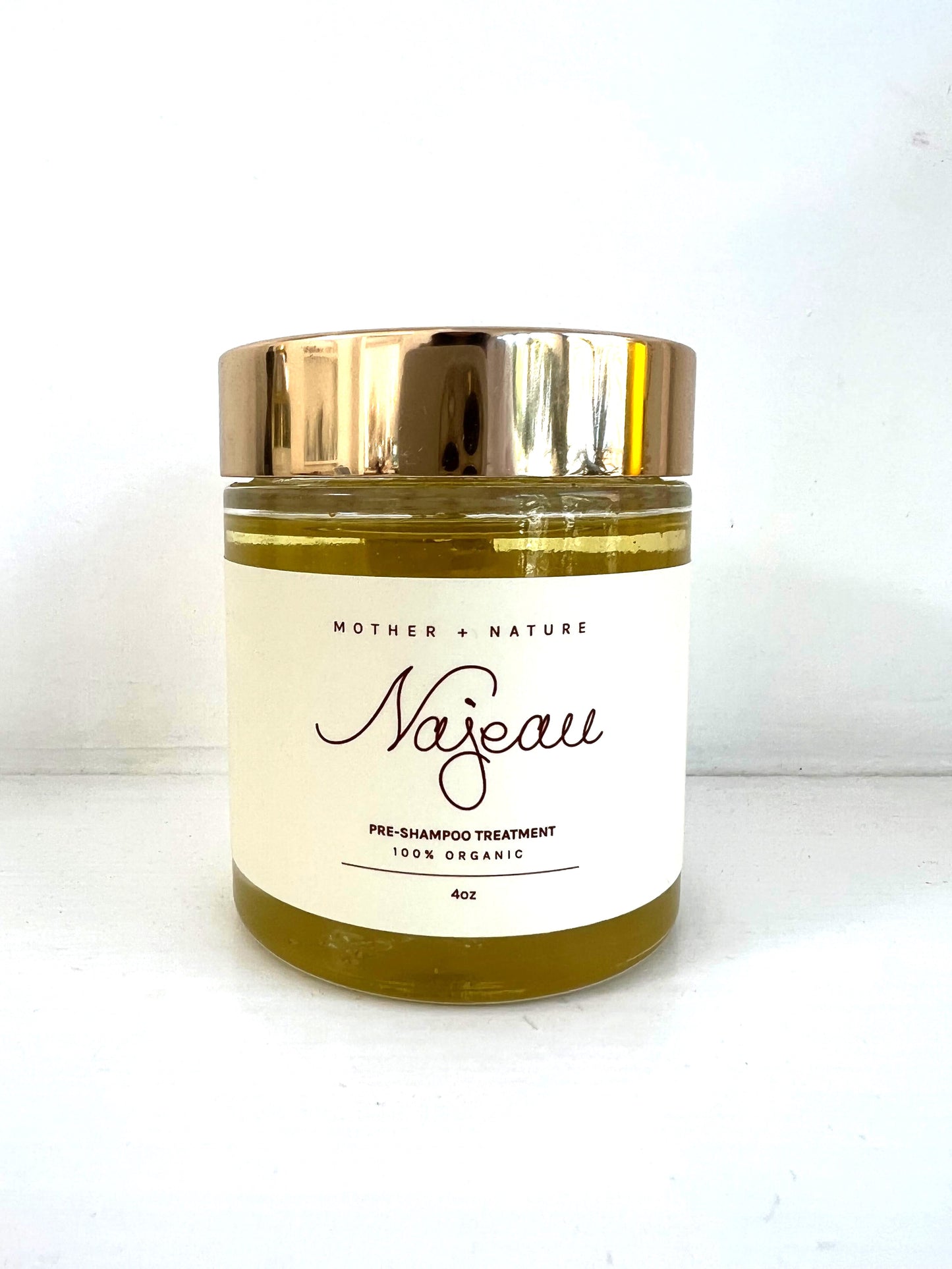 Najeau Scalp Treatment container with brass top and golden liquid.