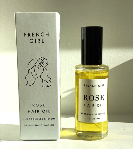 French Girl Rose Hair Oil in its glass bottle next to its white box.